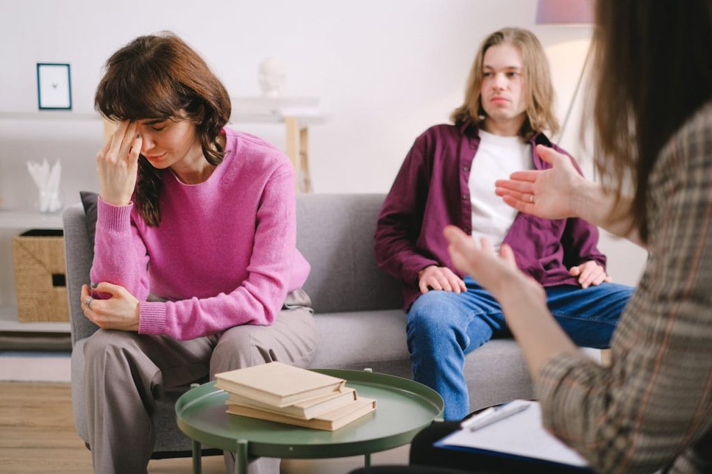 A couple undergoing therapy, expressing emotions on a sofa in a counseling office.